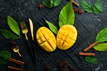 Fresh juicy mango cut into pieces with utensils. Top view. Rustic style.