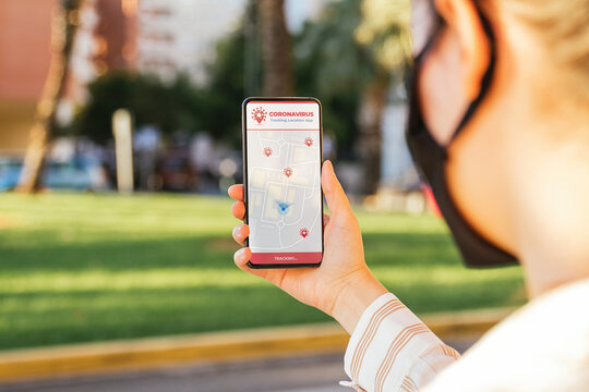 Stock Photo Of A Young Woman Using A Coronavirus Tracking App In Her Phone