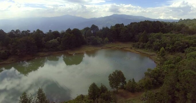 Pristine Green Guarne Lagoon in the Middle of the Woods near Medellin, Colombia on a Cloudy Day shot from in Smooth Travelling form Above