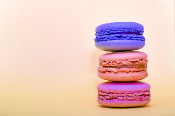 Multicolored macaroons in the form of a tower on a pink background. Colorful greeting card with delicious almond cookies. Sponge cakes on top of each other. Spaces for text, copy space.