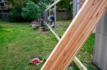 Building a new privacy fence. Carpenters working on wooded for new fence. Selective focus on lumber.