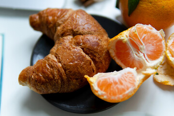 Composition with festive platter on a white table. Christmas mood. over white background coffee croissant tangerines and cinnamon. close-up.
