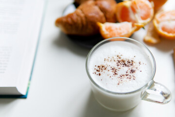Composition with festive assorted on a white table and a laptop and a book. Christmas mood. over white background coffee croissant tangerines and cinnamon. close-up.