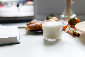 Composition with New Year's assortments on a white table. Christmas mood. on a white background coffee croissant tangerines and Christmas red balls. Close-up in the foreground of a mug with milk.
