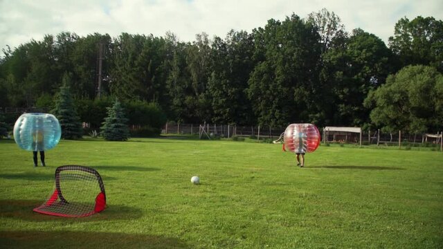 A young man scores a goal from the spot playing bubble football in the park.