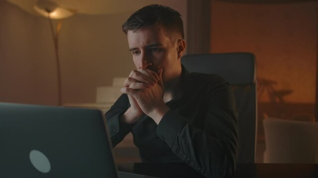 A man worries in front of a laptop screen for the result of a deal on shares on the stock exchange. Caucasian confident man nervous, crossed his fingers and waiting for the result of the deal