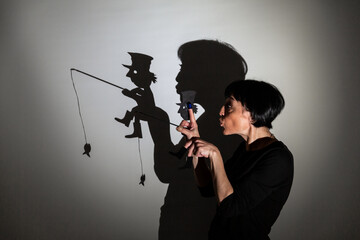 play shadow projected against a white background. a homeless man with a rod fishing