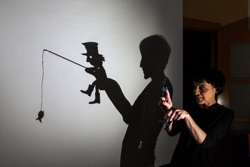 play shadow projected against a white background. a homeless man with a rod fishing