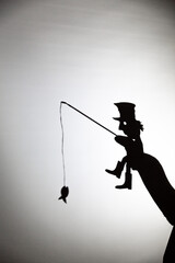 play shadow projected against a white background. a homeless man with a rod fishing