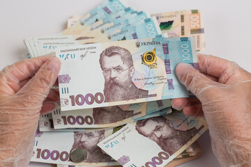 Money of Ukraine. Stack of ukrainian hryvnia banknotes in gloved hands on white. Hryvnia 1000 uah