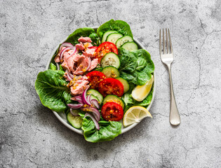 Canned tuna, tomatoes, cucumbers, romaine salad, red onion, olive oil salad - delicious healthy food on a grey background, top view