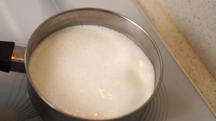 milk boils in a saucepan on the stove and pours on the stove. inattention in the kitchen. 