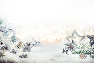 Christmas silver decorations on snow with fir tree branches and christmas lights. Winter Decoration...