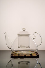 Empty glass teapot on a wooden stand. The picture was taken in a photo studio