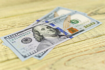 Hundred dollar bills on a wooden background.