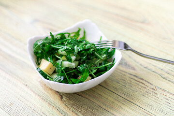 Rucolla salad with cheese on a wooden background.