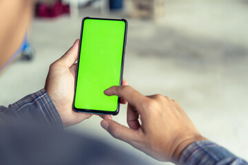 Mockup image of hand’s man holding black mobile phone with blank green screen in service shop.