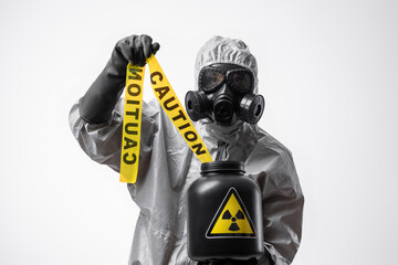 A man in a protective suit and gas mask holds a yellow tape 