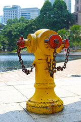 Typical old yellow fire hydrant with rusty chains on the sidewalk in Kuala Lumpur city on a sunny...