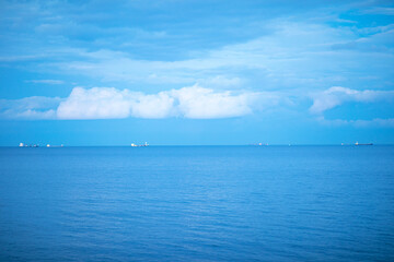 Naklejka na ściany i meble Calm blue sea with ships in the background.