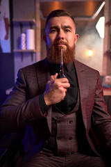 professional hair stylist is ready to cut your hair or beard, male in suit at work place, posing in dark room