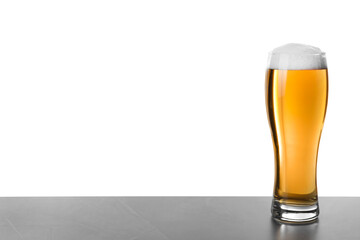 Glass of tasty beer on grey table against white background
