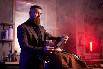 beauty shop for men concept. professional hairdresser shaving a beard to rich clients in a barbershop, brutal haircuts