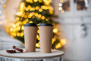 Coffee to go is on the table in the cafe.  Christmas mood is a warm beverage.  Mulled wine tea winter take away drink.  Reusable zero waste mug.  Two friends couple concept. New year Bokeh background 