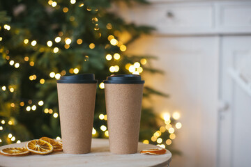 Two cups are on table. New year bokeh garland. Christmas mood. Couple in cafe relationship concept. Zero waste reusable cup mug. Homemade coffee to go. Hot beverage. Tea take away. orange snacks eco