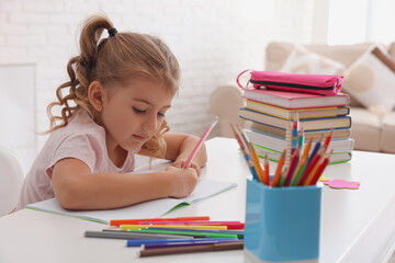 Cute little girl doing homework at table