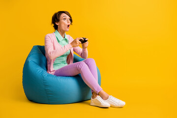 Full length body size photo of girl playing console with controller amazed in glasses isolated on bright yellow color background copyspace