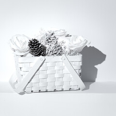 Minimal winter composition. Basket with white cones, roses and pumpkin.  Still life art