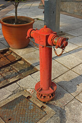Fototapeta na wymiar Typical old red fire hydrant with rusty chains on the sidewalk in Kuala Lumpur city