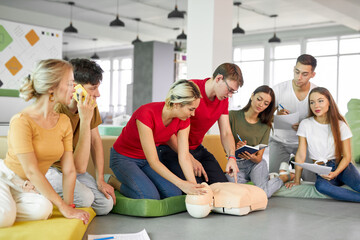 CPR class with young caucasian instructors speaking and demonstrating help first aid, cpr mannequin on the floor