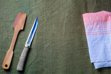 The wooden spatula and knife lie on a green ragcloth next to the napkin.