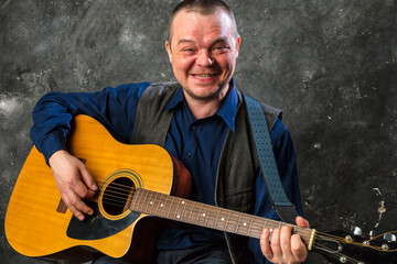 Mature musician plays acoustic guitar emotional studio portrait.