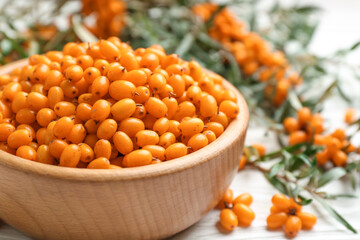 Fresh ripe sea buckthorn in wooden bowl, closeup