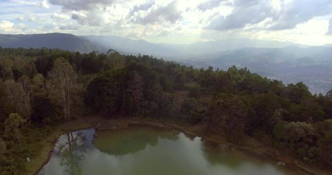 Pristine Green Guarne Lagoon in the Middle of the Woods near Medellin, Colombia on a Cloudy Day shot from in Smooth Travelling form Above