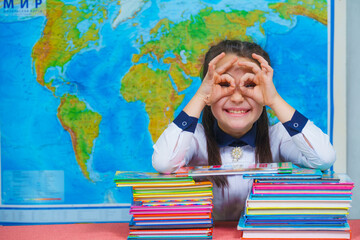 Portrait of a smart cute girl reading books on the background of the world map. Shows glasses with his hands