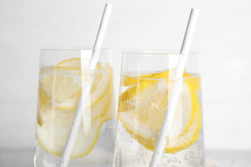 Soda water with lemon slices on light background, closeup
