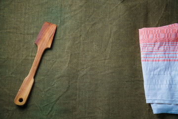 The wooden spatula lie on a green ragcloth next to the napkin.
