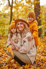 blonde adult woman with children in autumn forest, beautiful lady in hat and coat spend time with...