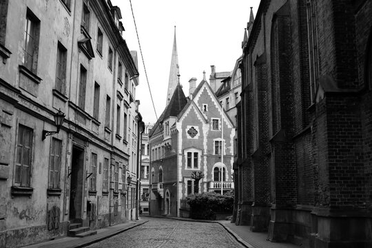 Dark mystical street of european city and gothic house, black and white photo