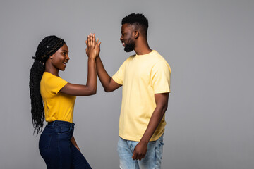 Obraz premium Excited emotional young cute african couple posing give a high five to each other.
