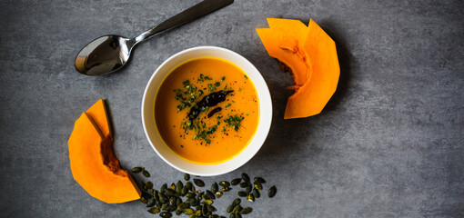 Homemade, fresh and good looking  pumpkin soup in white bowl on beautiful background, flat lay