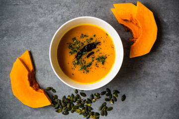 Homemade, fresh and good looking  pumpkin soup in white bowl on beautiful background, flat lay