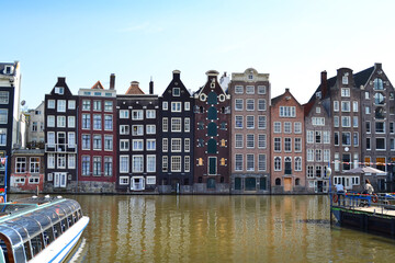 Fototapeta na wymiar Famous vintage buildings on the canal in Amsterdam. General landscape view at tradition Dutch architecture, The Netherlands.