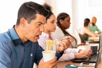 Latin mature business man eating and working in the office. meal, busy, food, snack concept. .