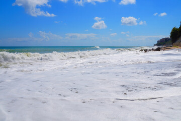 white sea foam on the beach on a sunny day