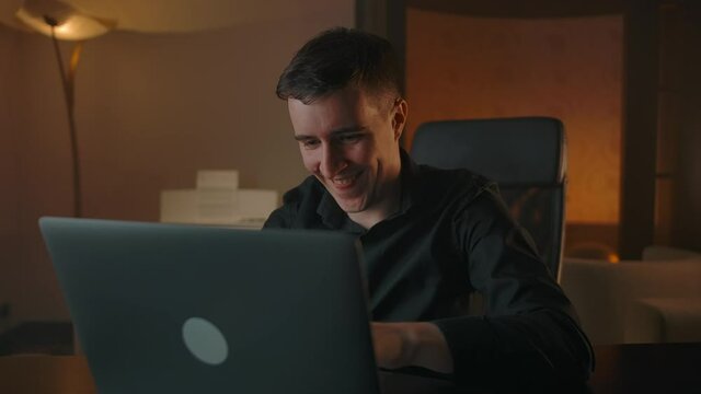 The mother-of-one rejoices in writing an angry comment on social media. Interior of modern cozy apartment in the evening. A man spoils the mood of content creators, dislike.